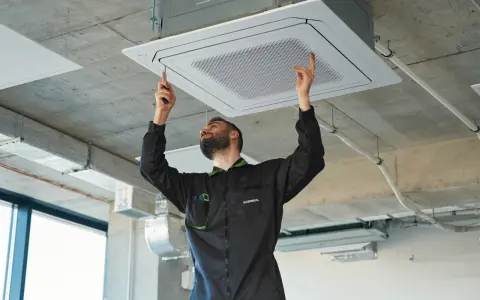 Técnico ajustando una unidad de cassette para la instalación de ventilación en un techo de hormigón.