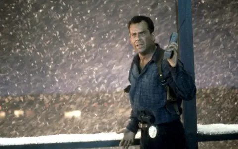 Bruce Willis som John McClane, mitt i snöstormen, med en gammal mobiltelefon i handen. En ikonisk scen från rollistan i Die Hard 2.