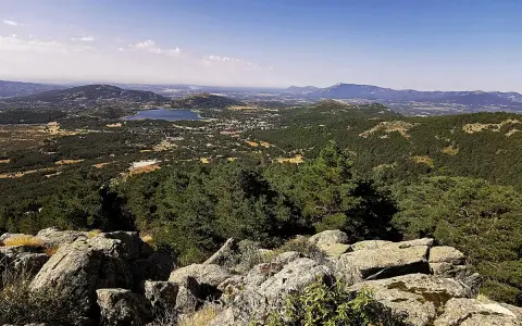 Vista panorámica del valle de la barranca, con un lago azul y montañas verdes bajo un cielo despejado.