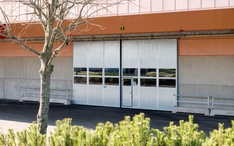 Två stora, vita skjutportar med fönster, redo att bygga för en verkstad.