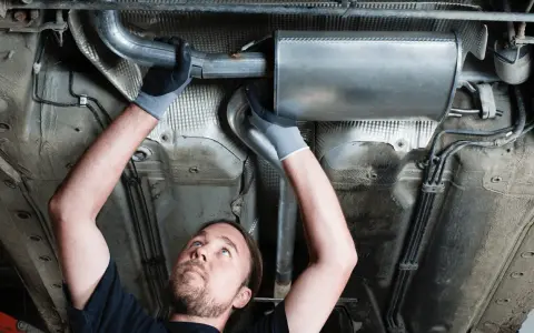Mechanic working on a car's exhaust system. This tune up consists of replacing a section of the exhaust pipe and muffler.