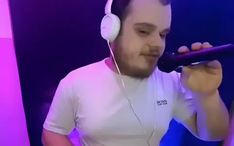 Młody dj akun w słuchawkach i białej koszulce z mikrofonem w ręku, w studiu z fioletowym oświetleniem.