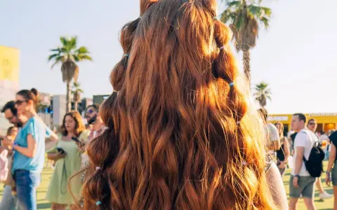 Peinados para festivales: cabello largo y ondulado con secciones recogidas en pequeñas coletas, ideal para disfrutar del sol y la música.