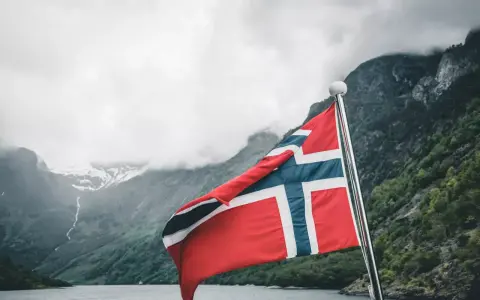 Norweska flaga na tle fiordu. Marzenie o pracy w Norwegii staje się rzeczywistością.