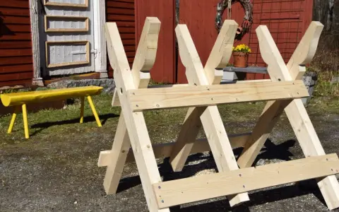 Nybyggd sågbock i trä, redo för att bygga ved. En gul bänk syns i bakgrunden.