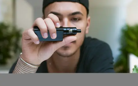 Joven con gorra negra sostiene un cigarrillo electrónico, mostrando sus claromizadores.