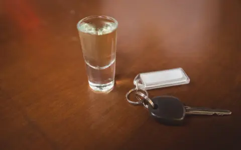 Kieliszek z alkoholem i kluczyki do samochodu. Pamiętaj, że kara za jazdę po pijanemu jest surowa.