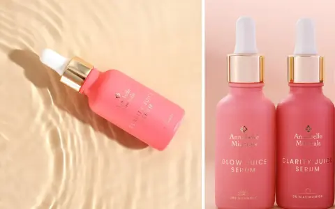 Różowe serum Annabelle Minerals z niacynamidem na trądzik. Dwa flakoniki z pipetką, jeden w wodzie, drugi obok.