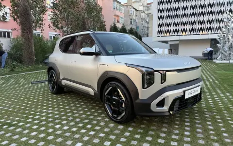 El ev2 kia, un SUV eléctrico plateado, descansa sobre un césped con baldosas cuadradas.