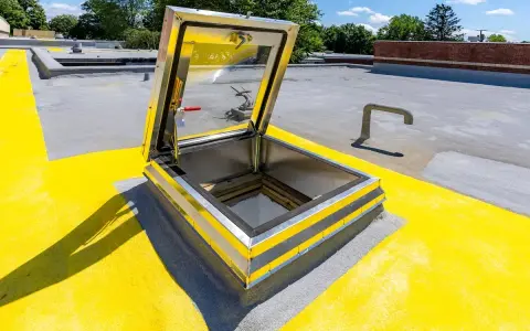 Porta di accesso al tetto aperta, con segnaletica gialla e grigia. La normativa per l'accesso al tetto è rispettata.