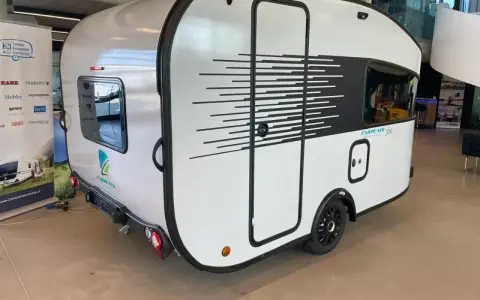 Biała przyczepa kempingowa CARPENTO 360 z czarnymi, dynamicznymi pasami. Idealna na wakacyjne podróże.