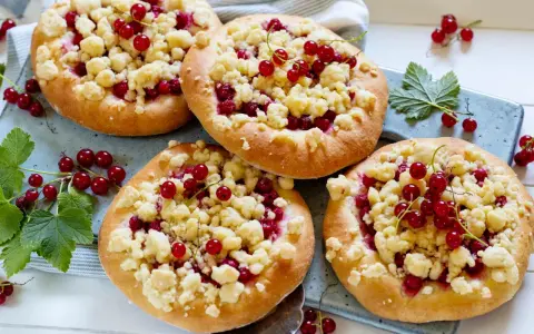 Vier kleine Küchlein mit Streuseln und roten Johannisbeeren, die den köstlichen jostabeere geschmack versprechen.