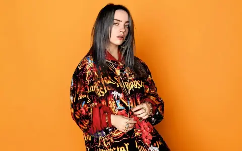 Billie Eilish w kolorowej bluzie, z mnóstwem złotych łańcuchów i pierścionków, jakby przygotowywała się do odebrania kolejnych nagród.