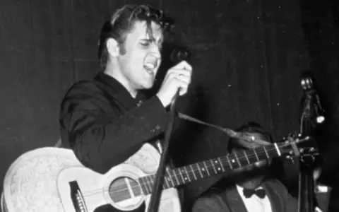 Elvis Presley singt mit Leidenschaft und spielt Gitarre. Ein historischer Moment, vielleicht sein erster Song.