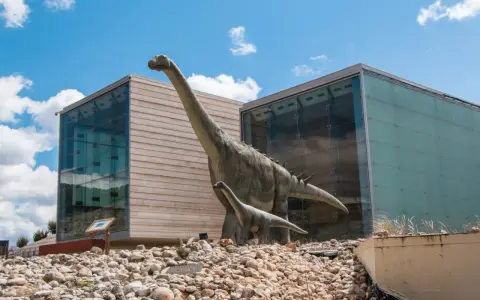 Modelos de dinosaurios frente a edificios modernos. Un plan perfecto para saber qué ver en Cuenca con niños.