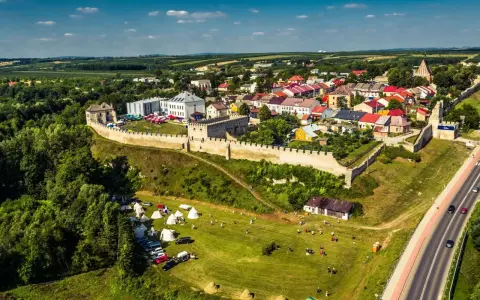 Widok z lotu ptaka na zamek i rynek w Szydłowie. Na trawiastym polu rozstawiono namioty, a w tle widać zabudowania miasta.
