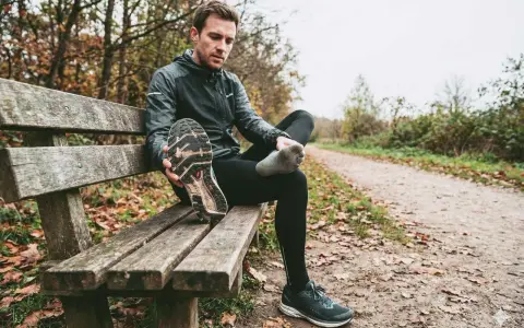 Runner seduto su una panchina controlla le sue scarpe da corsa, pensando a ogni quanto cambiarle per non incorrere in infortuni.