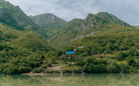 Zielone góry nad jeziorem, z domami i niebieskim dachem.