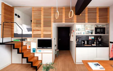Acogedor apartamento con **dormitorios con techos altos** elevados, escaleras de madera, cocina compacta y zona de estar.