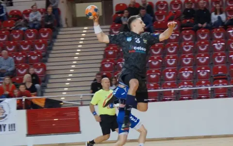 Kacper Grabowski w skoku do rzutu piłką ręczną, próbuje pokonać obronę przeciwnika.