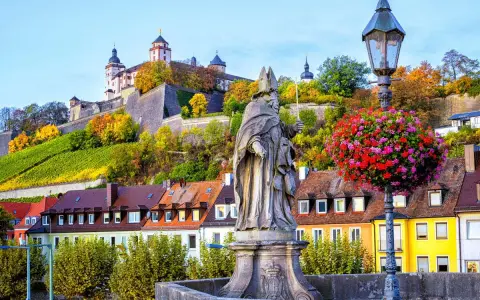 Statua sul ponte di Würzburg, con la fortezza in cima alla collina e i vigneti. Perfetto per un itinerario di 7 giorni sulla Romantische Straße.