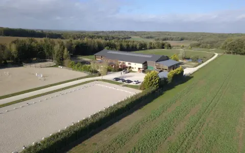 Vue aérienne d'une écurie avec manège et carrière de dressage. Le système de **carrière subirrigation** assure un sol parfait pour les chevaux.