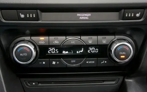 Panel sterowania klimatyzacją w samochodzie, z pokrętłami AUTO i DUAL, wyświetlaczem temperatury 20.5°C i ikonami nawiewu. Idealny do ozonowania klimatyzacji.