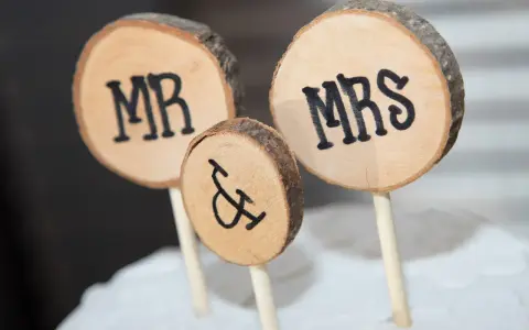 Drewniane krążki z napisami MR i MRS, symbolizujące Parę Młodą, ozdabiają tort.