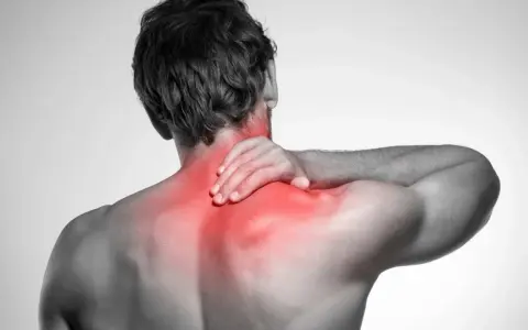 Uomo con mano sul collo e spalle rigide, evidenziate in rosso per indicare dolore.
