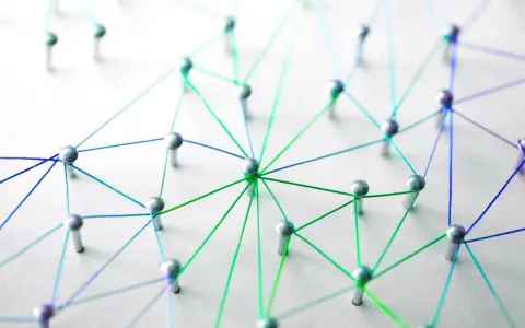 Netzwerk aus silbernen Pins und bunten Fäden auf weißem Untergrund.