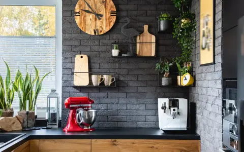 Estilo moderno para la decoracion pared cocina: reloj de madera, plantas, tazas y batidora roja.