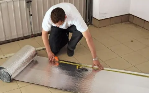 Mężczyzna mierzy materiał do ocieplenia bramy garażowej.