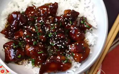 Aksamitny teriyaki kurczak w sosie, posypany sezamem i szczypiorkiem, podany na białym ryżu. Pyszne danie gotowe do spożycia.