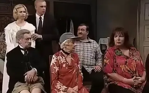 Scena z filmu "Tango" Mrożka. Grupa osób siedzi i stoi w pomieszczeniu.