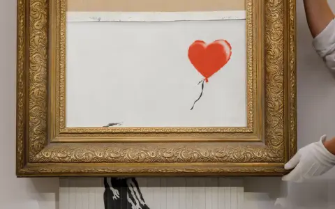 A framed Banksy artwork featuring a red balloon, hinting at how is Banksy rich.