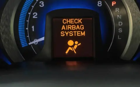 Na desce rozdzielczej świeci się pomarańczowa kontrolka poduszki powietrznej z napisem "CHECK AIRBAG SYSTEM" i ikoną pasażera.