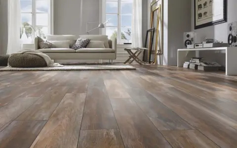 Sala de estar moderna con suelo de tarima AC5 de aspecto madera desgastada, sofá beige, alfombra y pufs.