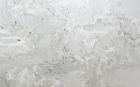 Textura de pared con manchas blancas y grises, como si la pintura se estuviera descascarando.