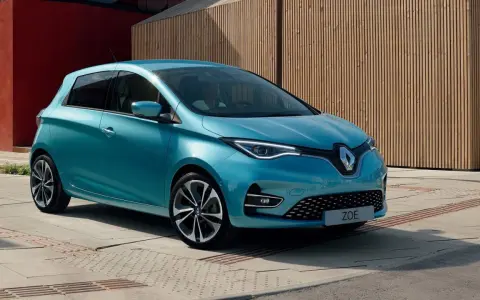 Błękitny Renault Zoe z nowoczesnymi światłami LED stoi na tle drewnianej elewacji.