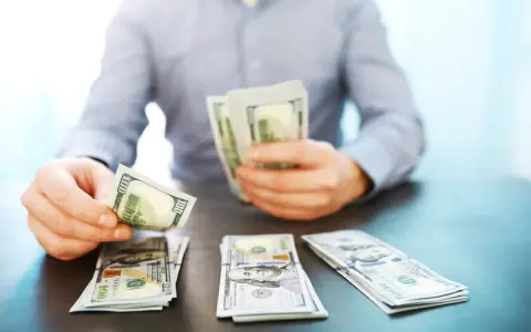 Mężczyzna liczy banknoty 100-dolarowe, symbolizujące dobrze płatne zawody i sukces finansowy.