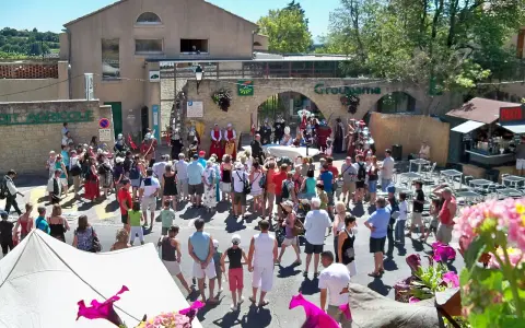 Foule en costume d'époque lors de la fête de la veraison, avec des musiciens et des stands.
