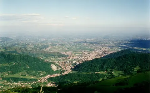 Vista panoramica dalla sella di Fadalto su una vasta pianura punteggiata di case e campi, con colline verdi in primo piano.