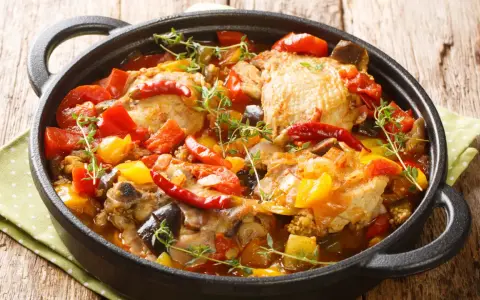 Sobracosce di pollo stufate con peperoni, pomodori, melanzane e peperoncino, guarnite con timo fresco.