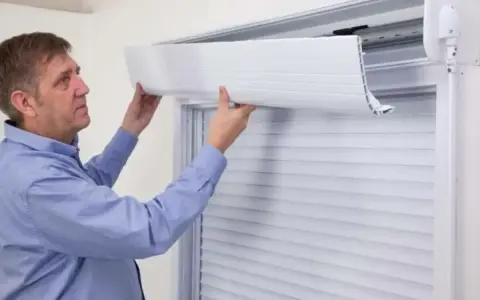 Un homme ajuste le tablier d'un volet roulant. Il montre comment relever un volet roulant électrique sans électricité.