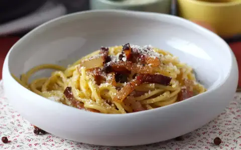 Spaghetti cremosi con guanciale croccante e pecorino, un'autentica ricetta della carbonara.