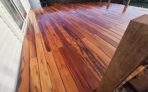 Planches de muiracatiara grisé, un bois exotique aux teintes chaudes et veinures marquées, formant une terrasse éclatante.