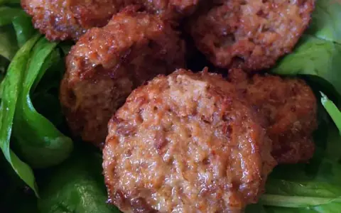 Polpette di lenticchie dorate e croccanti su un letto di spinaci freschi.