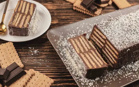 Tarta de chocolate y galletas, un postre casero con capas de galletas y crema de chocolate, espolvoreada con coco rallado.