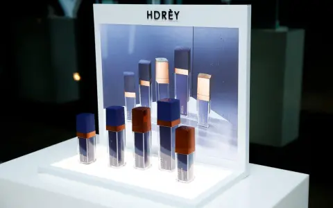 Eleganckie kosmetyki marki HDRÈY, w tym serum i olejki, prezentowane na białej, podświetlanej ekspozycji.