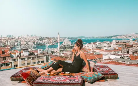 A woman enjoys a drink on a rooftop overlooking Istanbul, a scene straight out of a Rick Steves Turkey adventure.